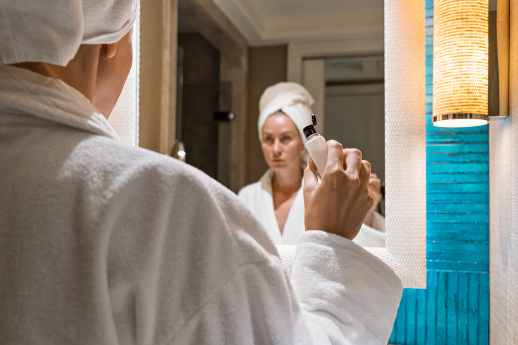 woman holding skincare product in bathroom mirror 2026 01 06 09 12 10 utc