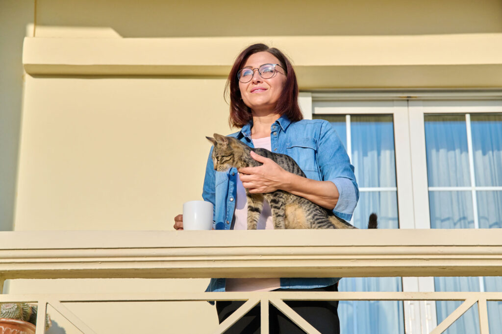 woman holds cat on balcony with coffee 2026 03 17 14 42 08 utc
