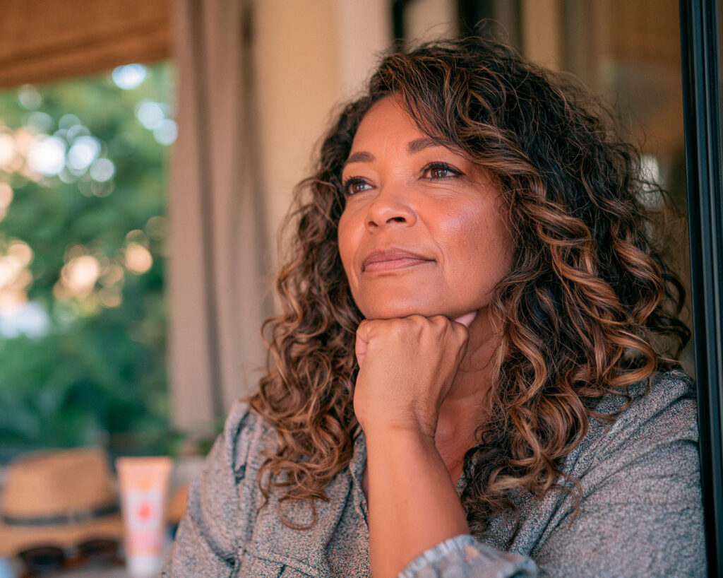 Woman gazing thoughtfully out window indoors