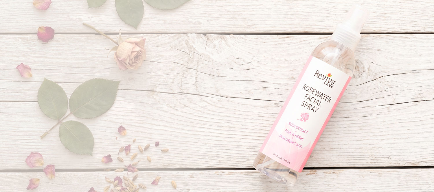 Rosewater facial spray bottle with rose petals on wood