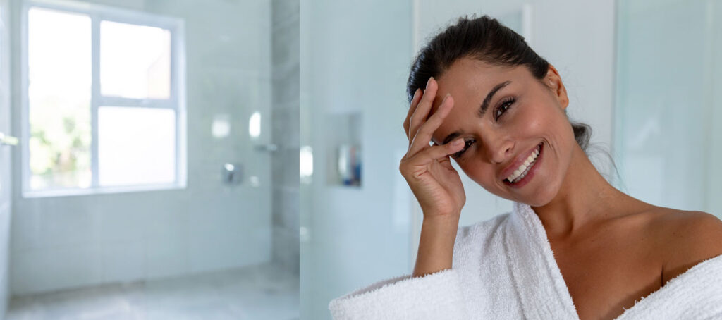 Smiling woman in bathrobe in a bright bathroom