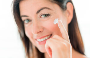 Woman applying moisturizer to her cheek