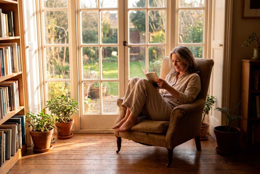 Woman reading book in sunlit window seat