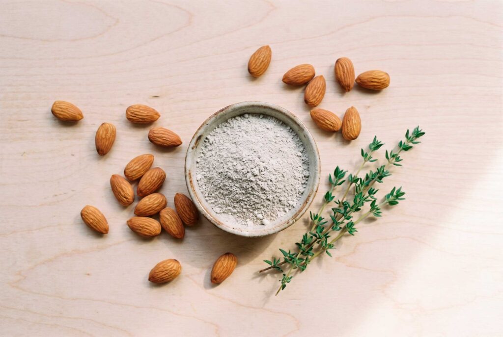 Almonds, almond flour, and thyme on wooden surface