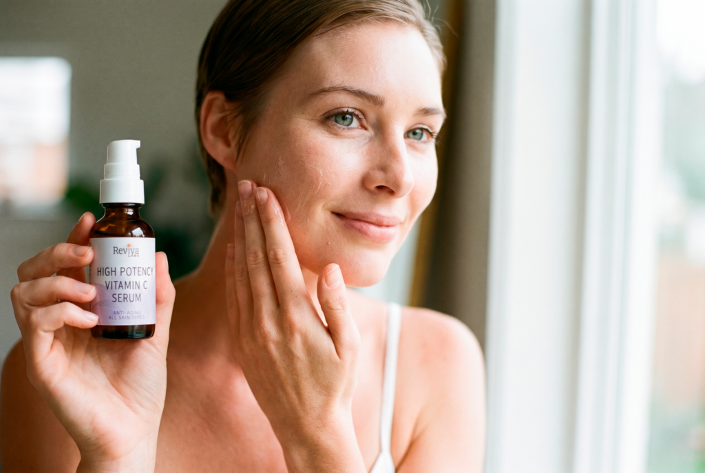 Woman applying vitamin C serum while holding bottle
