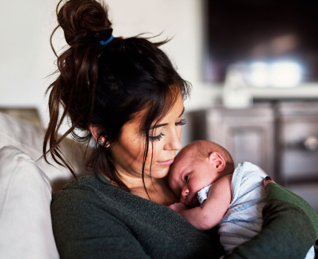 Mother tenderly cradles newborn baby against her chest