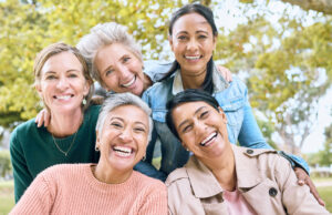 Five smiling women posing together outdoors