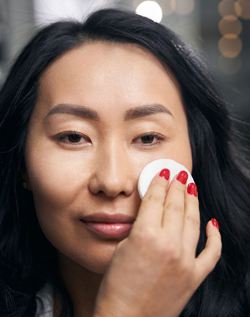Woman having makeup applied with cotton pad