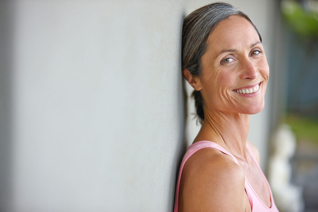 Smiling gray-haired woman leaning against a wall