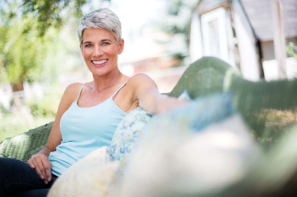 Smiling gray-haired woman relaxing on a sunny porch