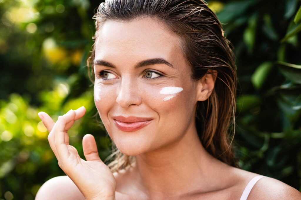 Woman applying sunscreen beneath her eyes outdoors