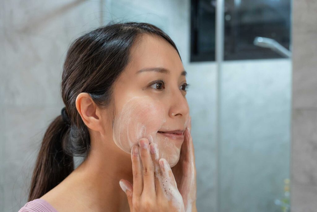 Woman washing her face with foaming cleanser